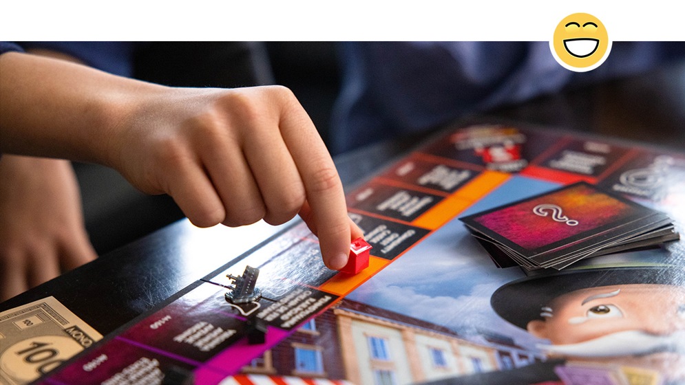 A person placing a house on the board in the game Monopoly. 